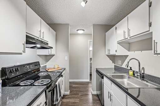 A kitchen with a black stove top oven and a black counter top.