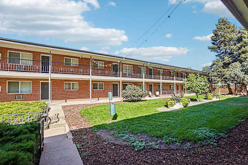 A red brick apartment building with a green lawn in front.