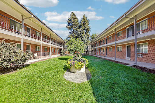 A courtyard with a tree and flower bed in the middle of a building complex.