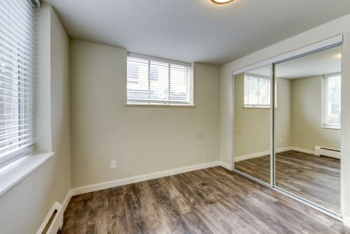 the spacious living room with mirrored closet doors and a large window