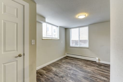 an empty living room with a white door and a window