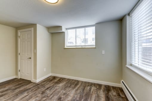 the spacious living room of an apartment with a door and window