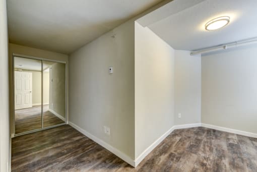 an empty living room with a mirrored wall and a door to a bedroom