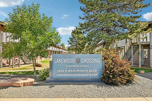 A sign for Lakewood Crossing Apartment Homes stands in front of a building.