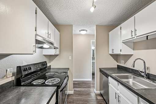A kitchen with a black counter top and white cabinets.