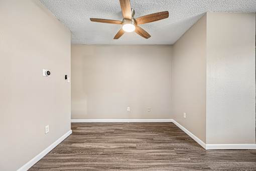 A room with a ceiling fan and wooden flooring.