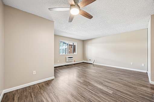 A room with a ceiling fan and wood flooring.