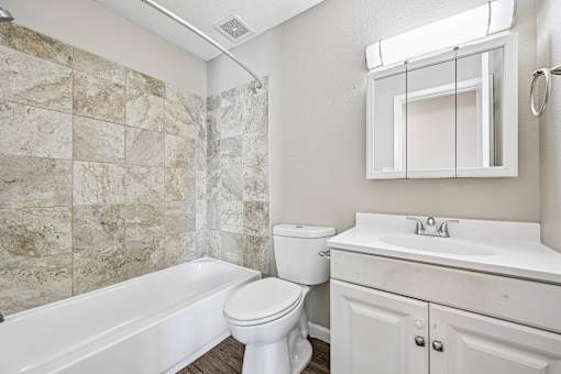 A bathroom with a white tub, toilet, and sink.