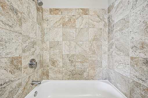 A white bathtub with a shower head and faucet.