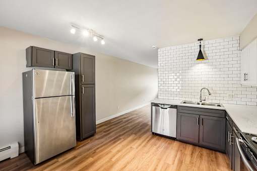 A kitchen with a stainless steel refrigerator and wooden floors.