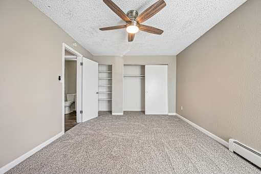 A room with a ceiling fan and carpeted floor.