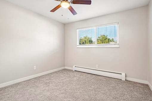 A room with a ceiling fan and a window with blinds.
