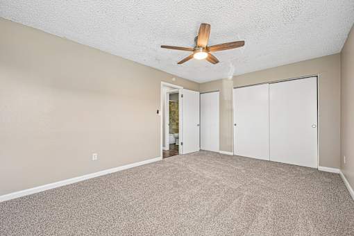 A room with a ceiling fan and carpeted floor.
