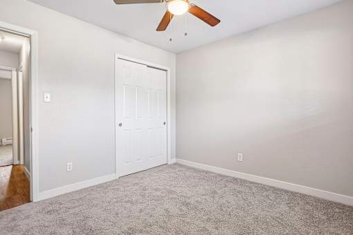A room with a ceiling fan and a white door.