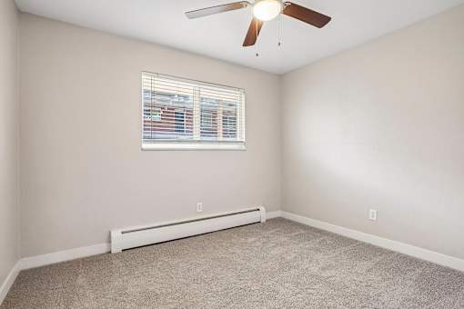 A room with a ceiling fan and a window with blinds.