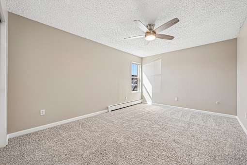 A room with a ceiling fan and carpeted floor.
