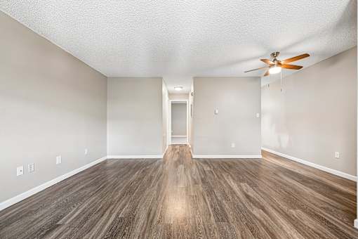 A room with a ceiling fan and wooden flooring.