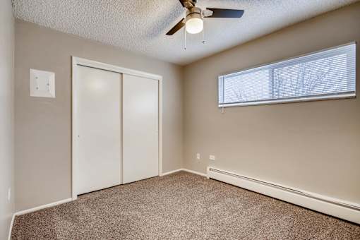 A room with a ceiling fan and a window with blinds.