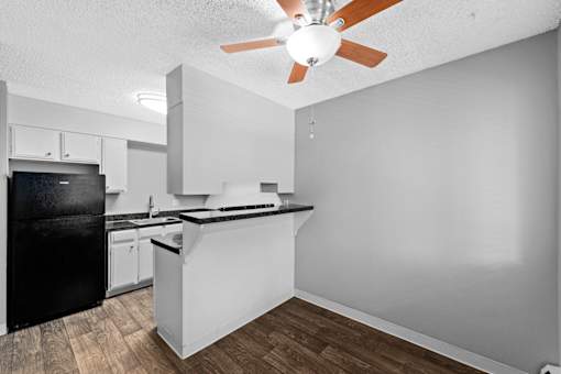 A kitchen with a black fridge and a white counter.