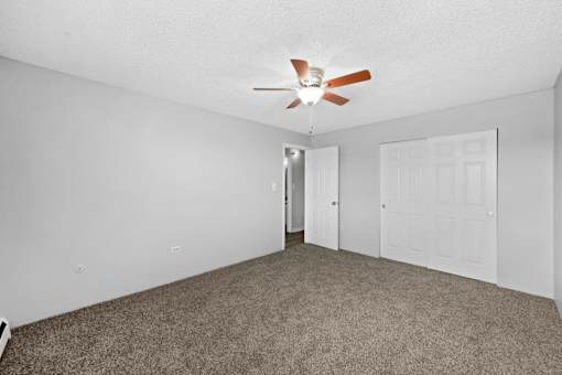 A room with a ceiling fan and carpeted floor.