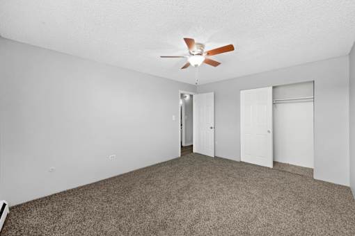 A room with a ceiling fan and carpeted floor.