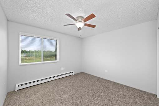 A room with a ceiling fan and a window with blinds.