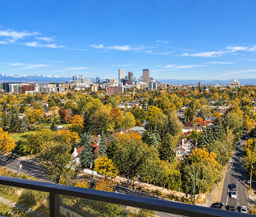 A cityscape with a mix of residential and commercial buildings, surrounded by trees with autumn foliage.