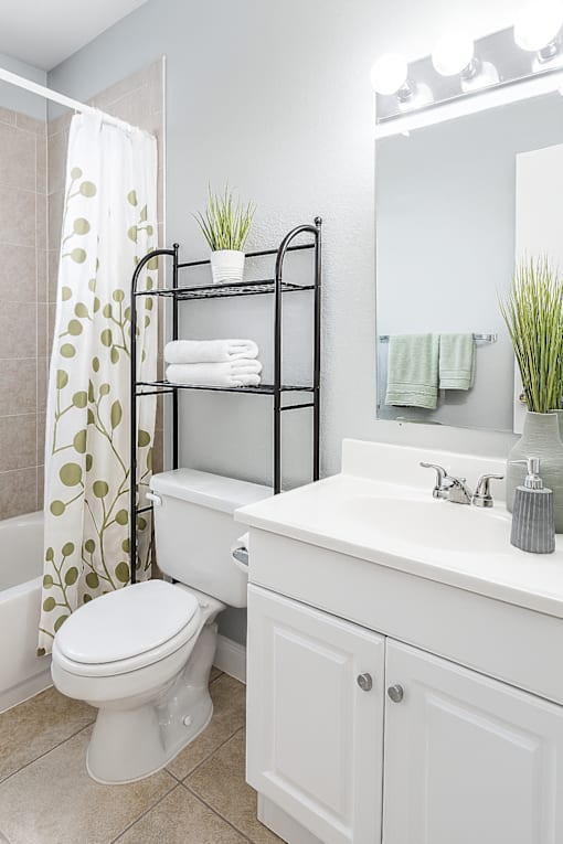 A white bathroom with a toilet, sink, and a mirror.
