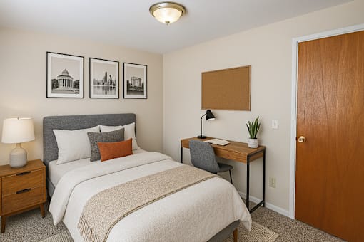 A bedroom with a bed, desk, and pictures on the wall.