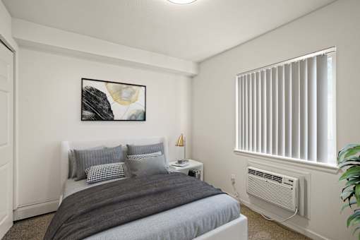 A bedroom with a bed, nightstand, and a window with blinds.