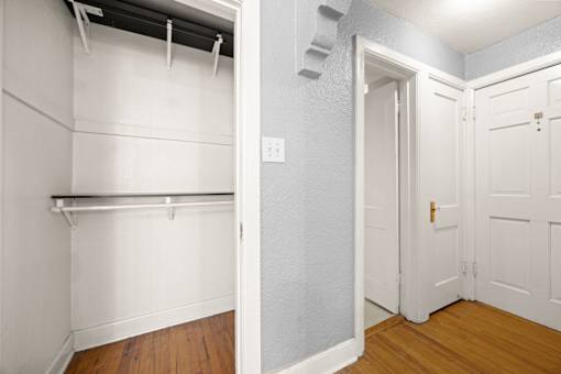 A white closet with a shelf and a white door.