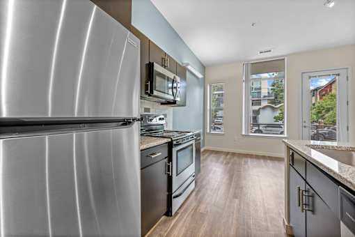 A modern kitchen with a stainless steel refrigerator and black appliances. at B Street Lohi Apartments, Colorado