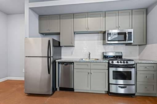 A kitchen with a refrigerator, oven, and microwave.