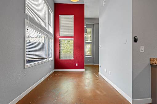 A room with a red door and a window with blinds.