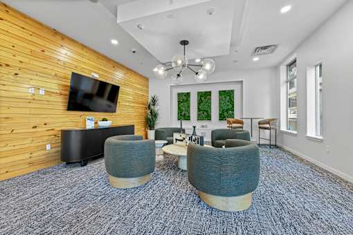 A room with a wooden wall and grey chairs.