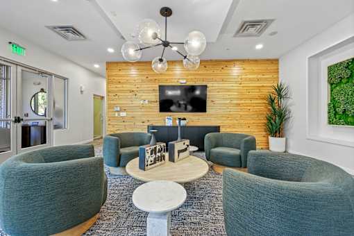 A modern waiting room with grey chairs and a wooden wall.