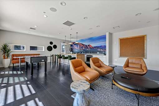 A modern living room with a large painting on the wall and a long black couch.
