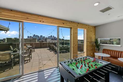 A foosball table is in the middle of a sunny room with sliding glass doors.