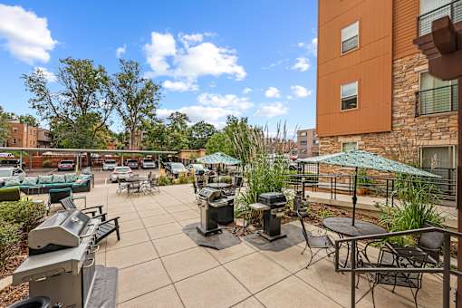 A patio with a grill and chairs.