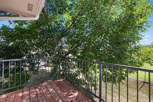 A balcony with a metal railing and a wooden floor.