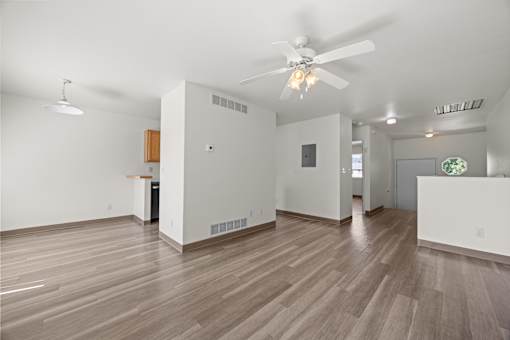 A room with a ceiling fan and wooden flooring.