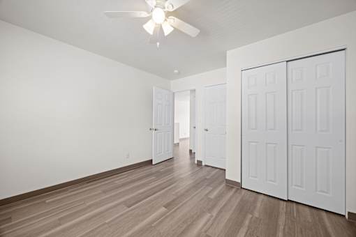 A room with a ceiling fan and white doors.
