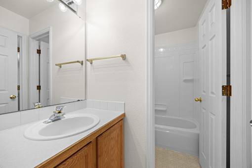 A white bathroom with a sink and a bathtub.