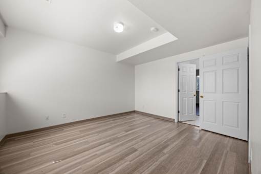 A room with a white door and wooden flooring.