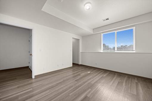 A room with a large window and wooden flooring.