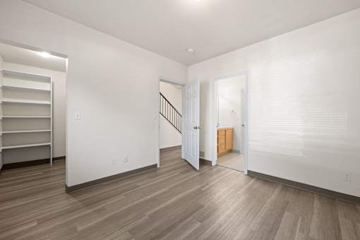 A white room with a wooden floor and a staircase.