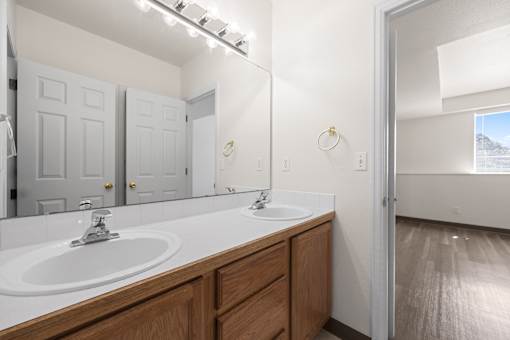 A bathroom with a white sink and wooden cabinets.