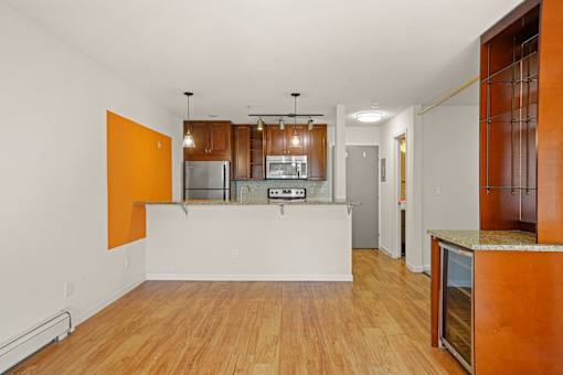 A kitchen with a white counter and orange accent wall.