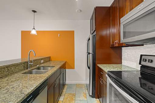 A kitchen with a sink, refrigerator, and microwave.