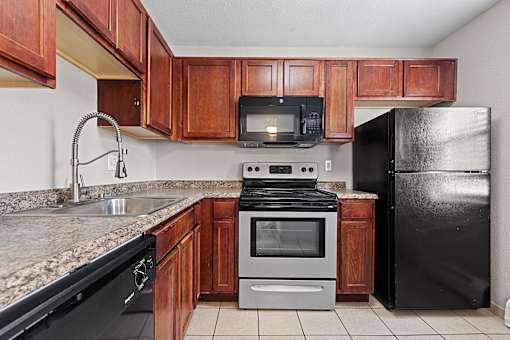 A kitchen with black appliances and wooden cabinets.